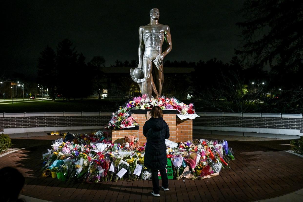 A visitor takes a moment at the Sparty statue after a vigil at Michigan State University on Wednesday, Feb. 15, 2023, honoring the victims of Monday’s mass shooting in East Lansing.