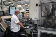 An employee wearing a protective face mask works at a factory of manufacturer Valeo, during a visit of French President Emmanuel Macron, in Etaples