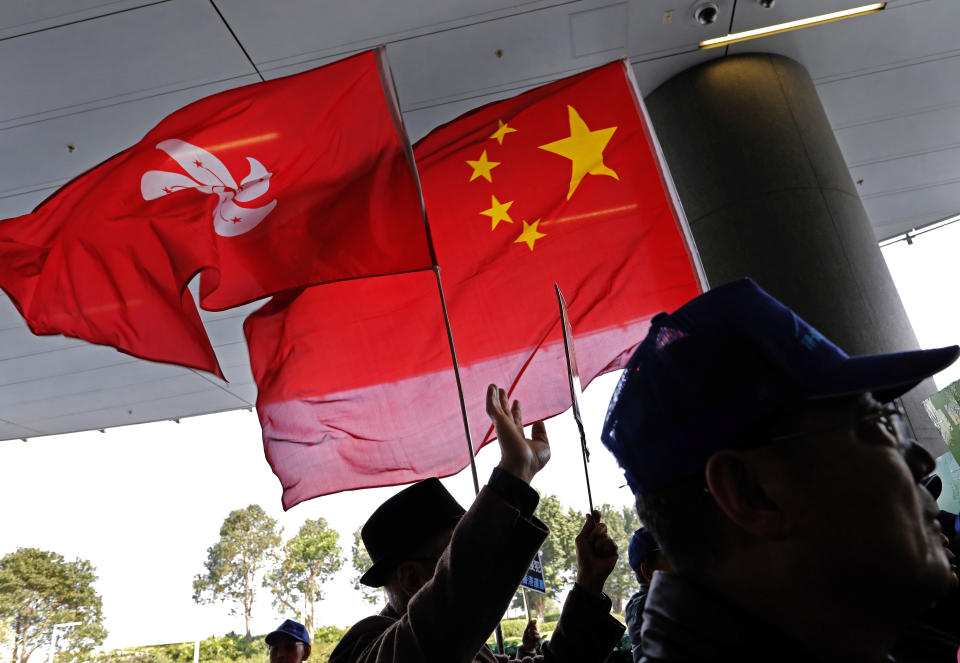 Pro-Beijing protesters raise the Chinese National flag and the Hong Kong flag during a protest outside Legislative building in Hong Kong, Wednesday, Jan. 23, 2019. Hong Kong’s legislature has taken up for consideration a bill that punishes anyone who "publicly and intentionally insults" the Chinese national anthem with up to three years in prison. (AP Photo/Vincent Yu)