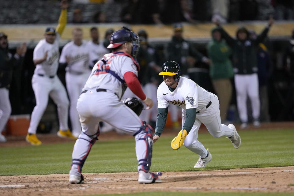 Oakland Athletics' Max Schuemann, right, slides into home plate past Washington Nationals catcher Riley Adams (15) to score the winning run on a single by Lawrence Butler during the 10th inning during a baseball game in Oakland, Calif., Friday, April 12, 2024. (AP Photo/Tony Avelar)