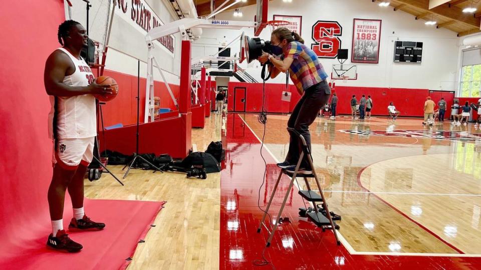 News & Observer photojournalist Kaitlin Kaitlin McKeown stands on a ladder to photograph NC State Center DJ Burns during the Wolfpack’s media day, Sept. 21, 2023.