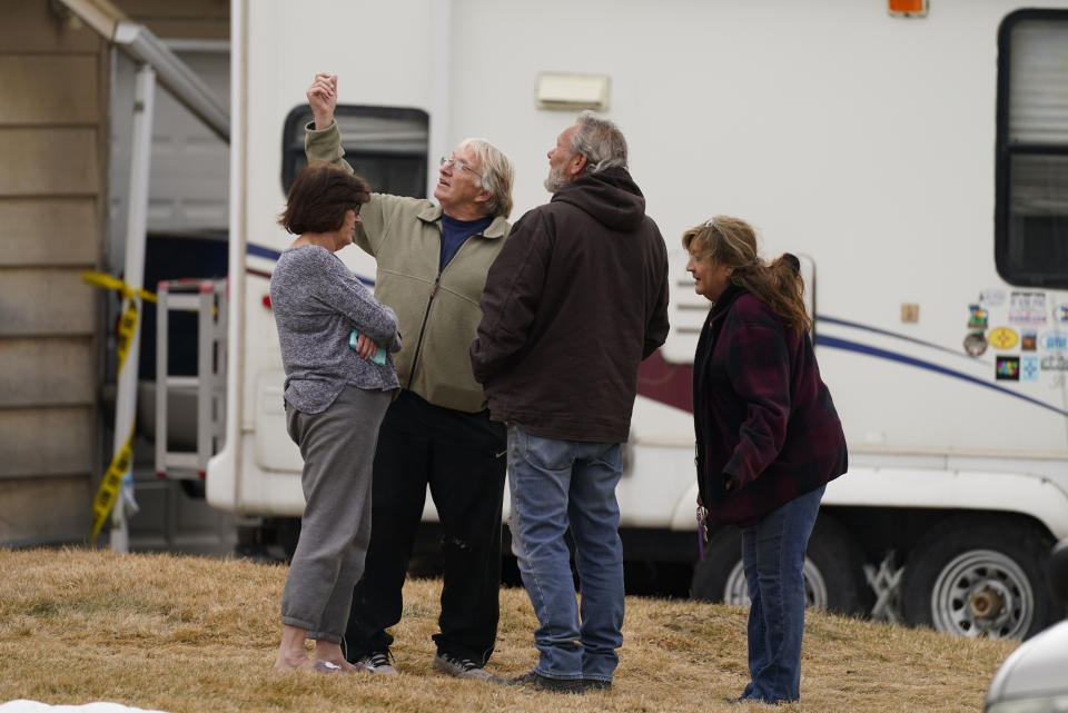 Neighbors gather on the lawn next to the home of Kirby Klements after a piece of debris from an airplane crushed the man's pickup truck parked next to his home in Broomfield, Colo., as the plane shed parts while making an emergency landing at nearby Denver International Airport Saturday, Feb. 20, 2021. (AP Photo/David Zalubowski)