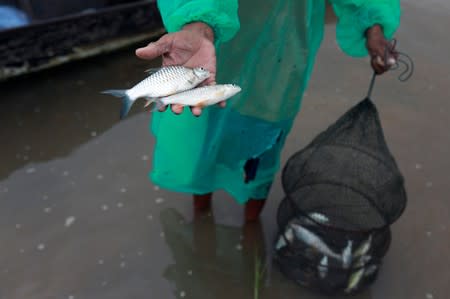 Fisherman shows his catch as he fishes in the Mekong River in Nakhon Phanom