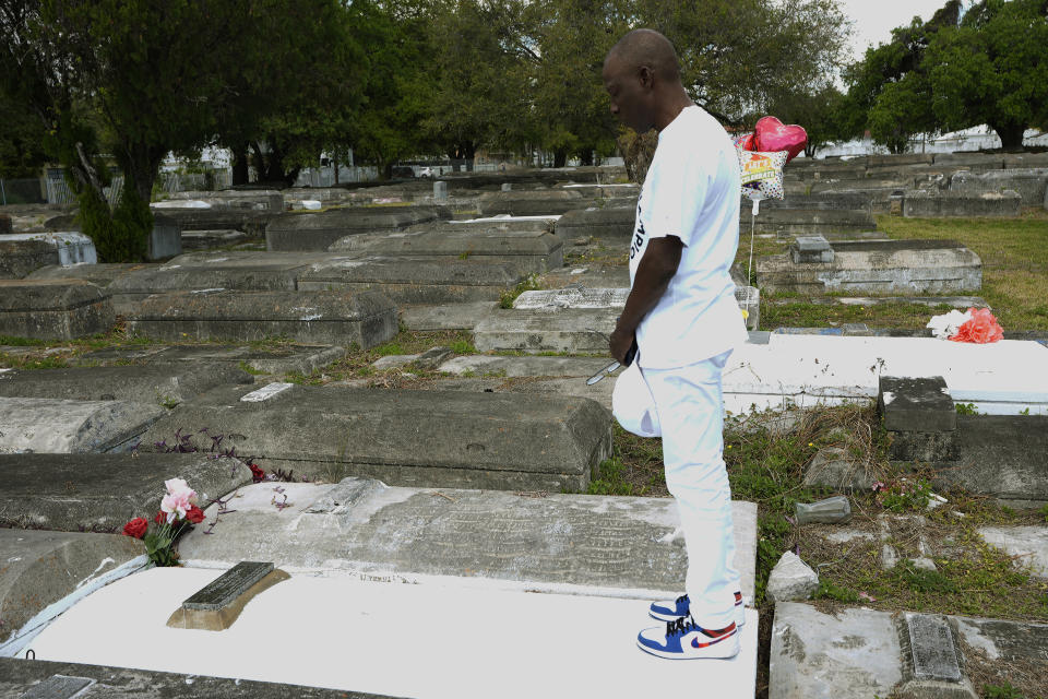 Jessie Wooden prays at the foot of his mother's grave at the Lincoln Memorial Park Cemetery, Monday, Feb. 26, 2024, in the Brownsville neighborhood of Miami. Wooden bought the cemetery after finding out that his mother, Vivian, who died when he was an infant, was buried there. “All my life I didn’t know her. All I knew that mom was gone,” he says. “For me to be able to come where she’s resting at and be able to just to say a little prayer and talk to her, oh, that means so much to me.” (AP Photo/Marta Lavandier)