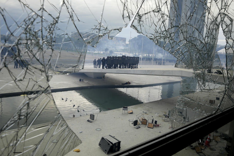FILE - Police stand on the other side of a window shattered by supporters of outgoing President Jair Bolsonaro, who stormed the Planalto presidential palace in an alleged bid to forcefully restore him to office, in Brasilia, Brazil, Jan. 8, 2023. (AP Photo/Eraldo Peres, File)