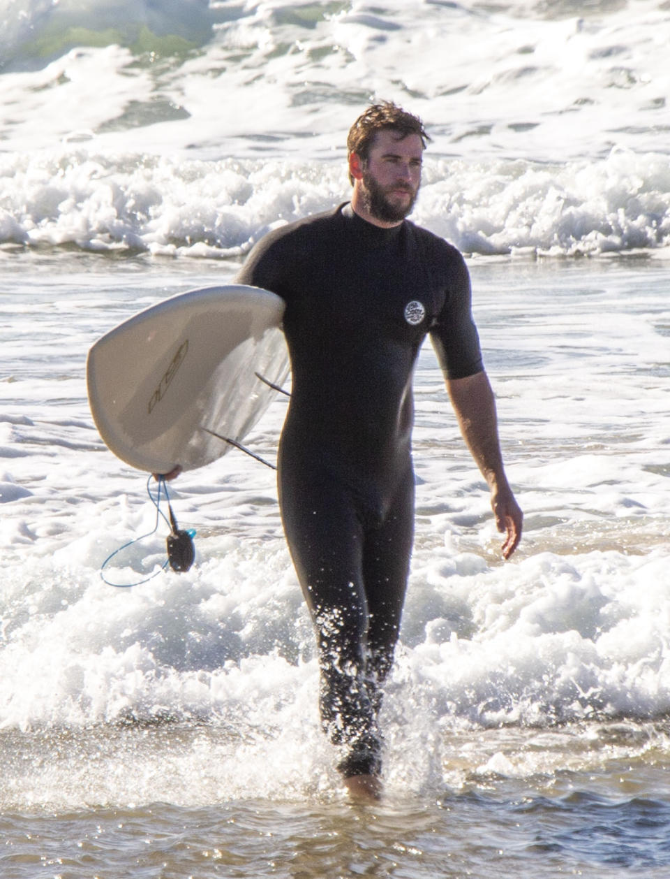 <p>Liam Hemsworth hits the beach on Friday with brothers Luke and Chris (not pictured) in Byron Bay, Australia.</p>