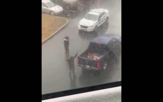 This screen grab is from a video that shows a Halifax police officer who appears to be aiming a weapon at a man with his hands up. The officer in the video has been placed on administrative duties, Halifax Regional Police Chief Dan Kinsella said Saturday. (Trayvone Clayton/Facebook - image credit)