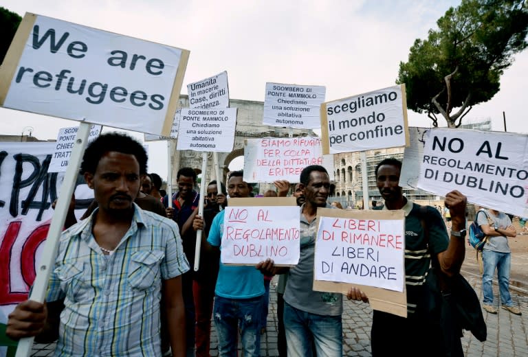 Participants hold signs reading "We are refugees" and "We are refugees because of the Eritrean dictatorship" during a demonstration in downtown Rome to mark World Refugee Day on June 20, 2015