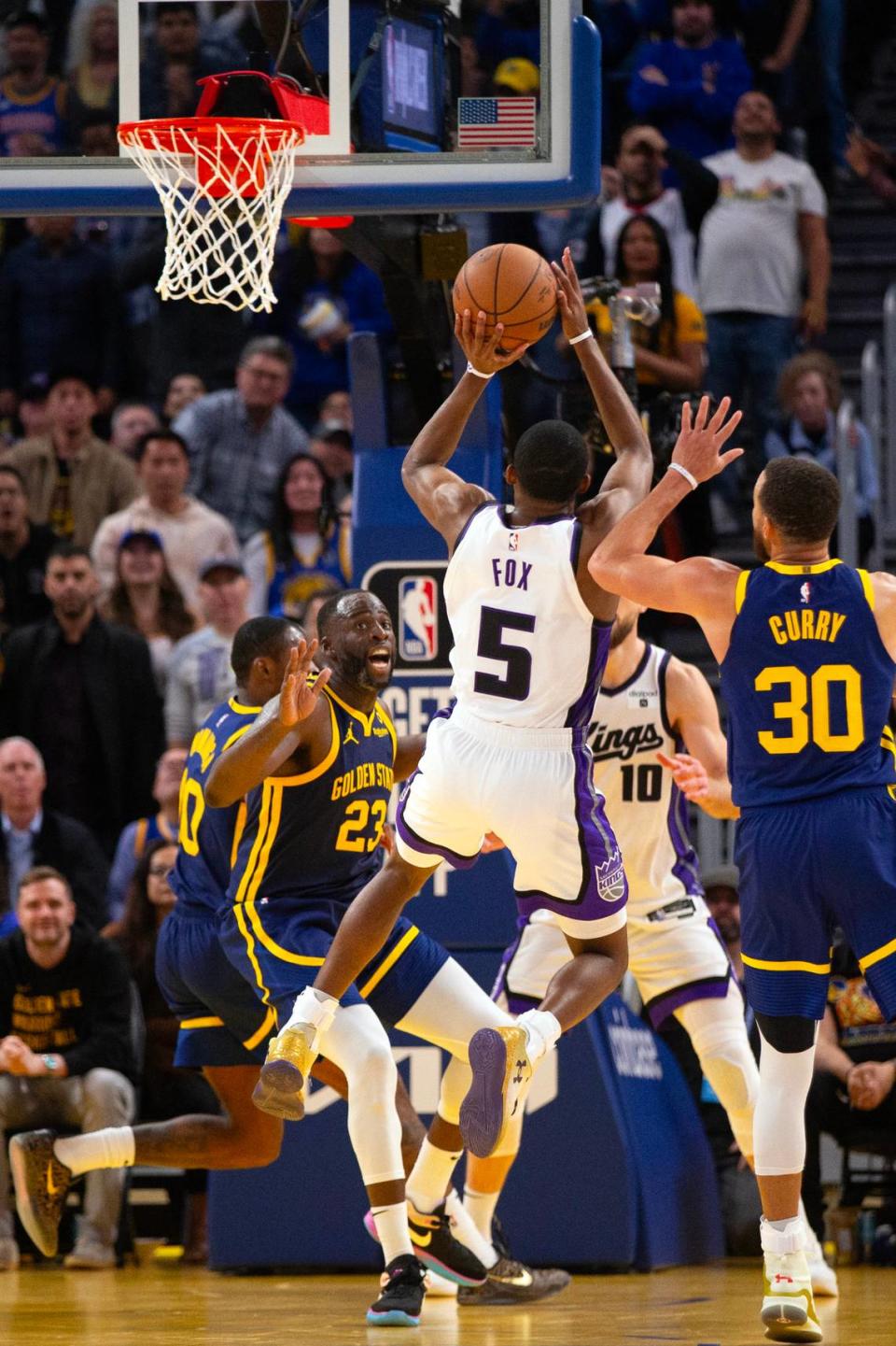 Sacramento Kings guard De’Aaron Fox (5) puts up a shot between Golden State Warriors defenders Draymond Green (23) and Stephen Curry (30) during the fourth quarter Thursday, Jan. 25, 2024, at Chase Center in San Francisco.