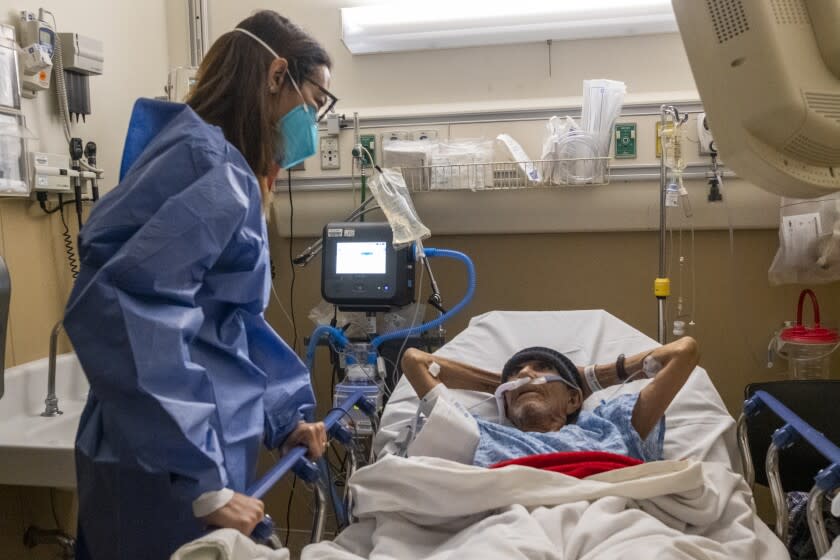 MISSION HILLS, CA - JANUARY 12: Dr. Marwa Kilani, left, the director of palliative care talks with Jose Luis Zarate Ventrura's hand at Providence Holy Cross Medical Center on Wednesday, Jan. 12, 2022 in Mission Hills, CA. Ventura is Covid19 positive. Dr. Kilani spends time with him listening to him. (Francine Orr / Los Angeles Times)