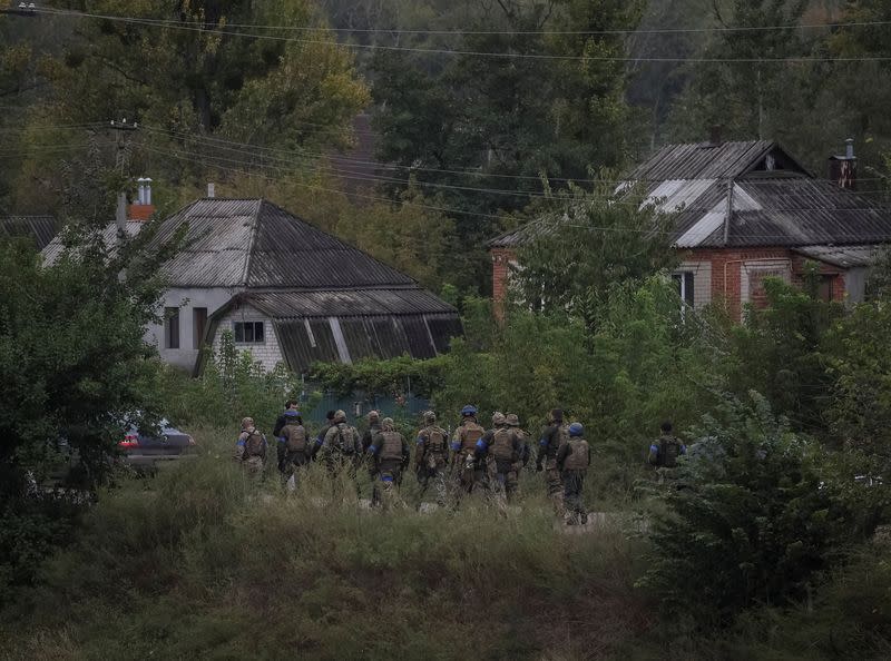 Ukrainian servicemen walk, as Russia's attack on Ukraine continues, in the town of Izium