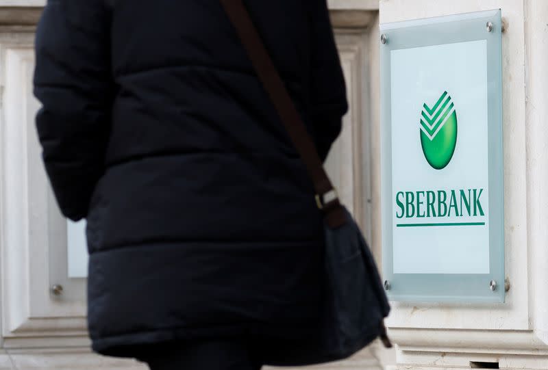 A person passes the logo of the Russian Sberbank Europe AG bank headquarters in Vienna