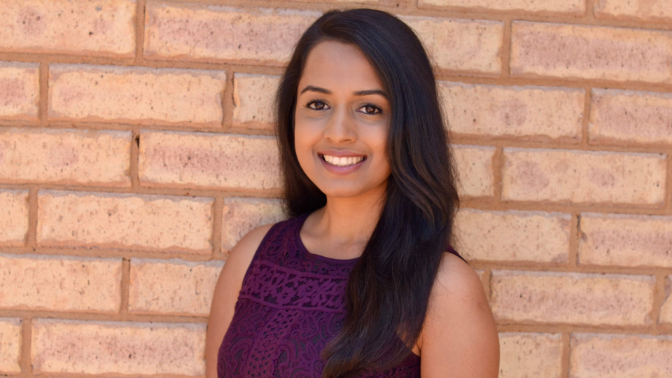 SkilledSmart founder Paridhi Jain smiling in front of a brick wall.