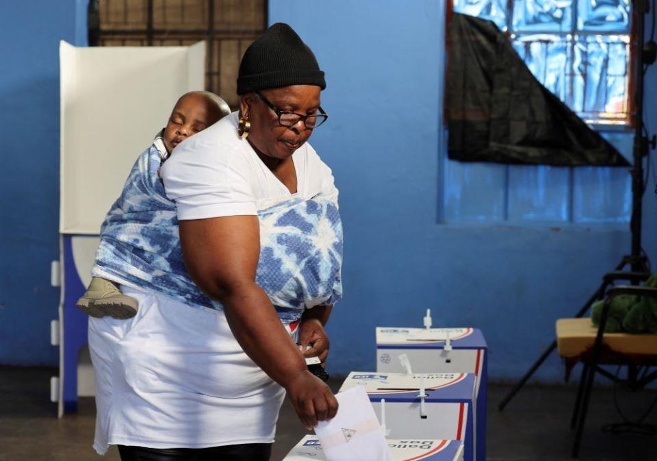 A woman with a child votes at Mponegele Primary School during the South African elections in Seshego, Limpopo Province, South Africa May 29, 2024. 