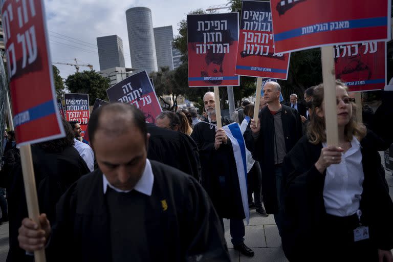 Legisladores israelíes sostienen carteles durante una protesta contra los cambios radicales en el sistema de justicia del país planeados por el nuevo gobierno conservador, afuera de la Corte de Distrito en Tel Aviv, Israel, el jueves 12 de enero de 2023. (AP Foto/Oded Balilty)