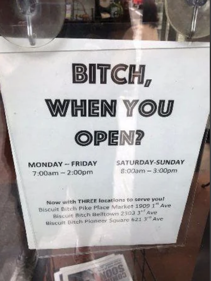 Signage with humorous tone lists business hours and locations for 'Biscuit Bitch' café