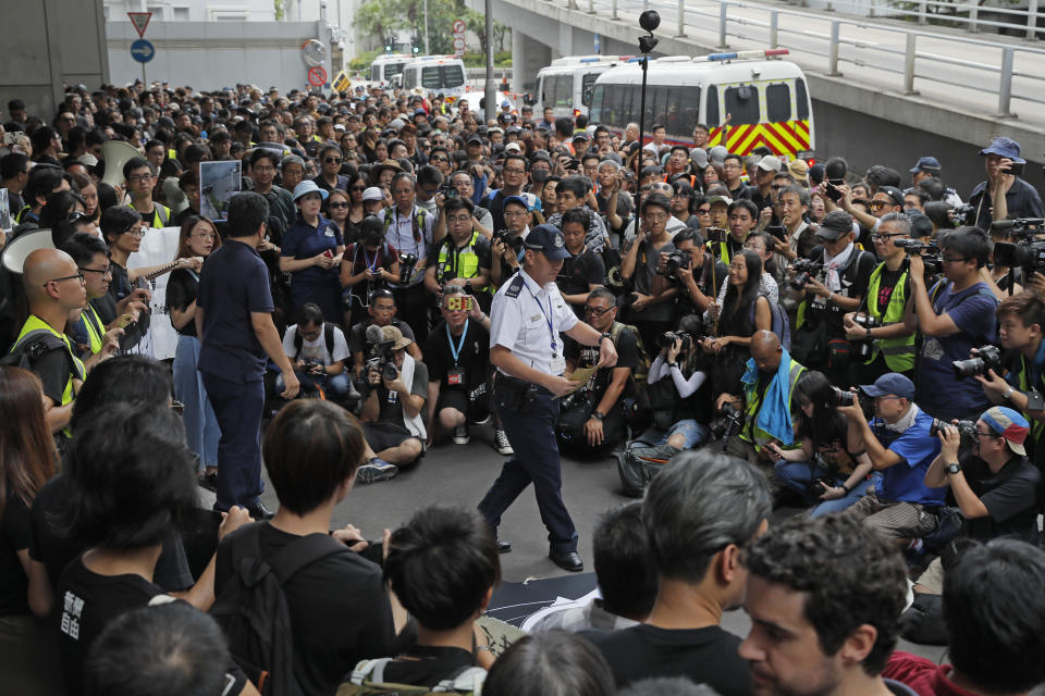 A police officer, center, received a letter as hundreds of journalists attend a silent march outside the police headquarters in Hong Kong, Sunday, July 14, 2019, demanding police to stop assaulting journalists and obstructing reporting. (AP Photo/Kin Cheung)