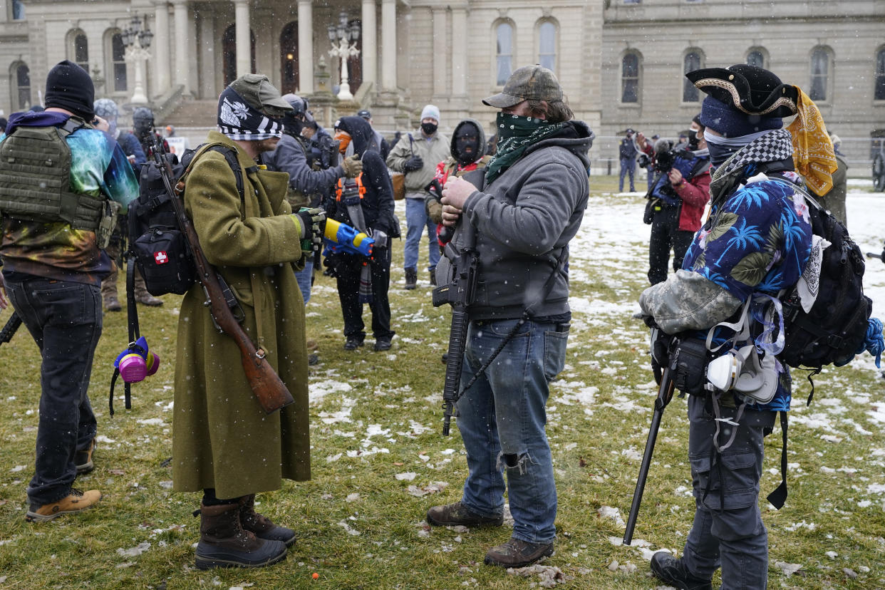 Men with rifles stand outside the State Capitol, Sunday, Jan. 17, 2021, in Lansing, Mich. (AP Photo/Carlos Osorio)