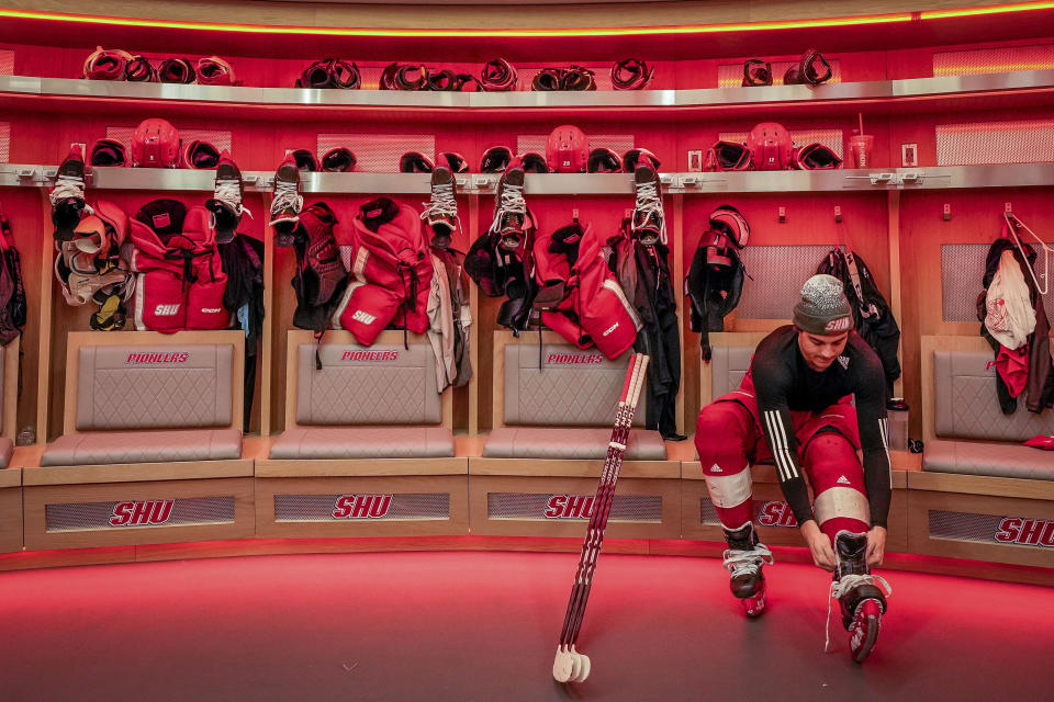 Men's forward Kevin Lombardi laces his skates in the locker room of the newly constructed NCAA college hockey Martire Family Arena on the campus of Sacred Heart University in Fairfield, Conn., Monday, Jan 9, 2023. (AP Photo/Bryan Woolston)