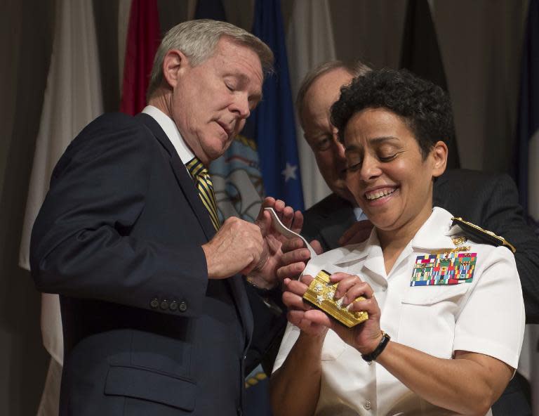 Adm. Michelle Howard lends a hand to US Secretary of the Navy Ray Mabus as he and Wayne Cowles (C), Howard's husband, put four-star shoulder boards on her service uniform during her promotion ceremony on July 1, 2014 in Washington, DC