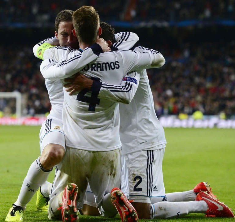 Real Madrid's Argentinian forward Gonzalo Higuain (L) celebrates next to Real Madrid's French defender Raphael Varane (R) and Real Madrid's defender Sergio Ramos after scoring during the UEFA Champions League quarter-final first leg football match Real Madrid vs Galatasaray on April 3, 2013 at Santiago Bernabeu stadium in Madrid. Real won 3-0