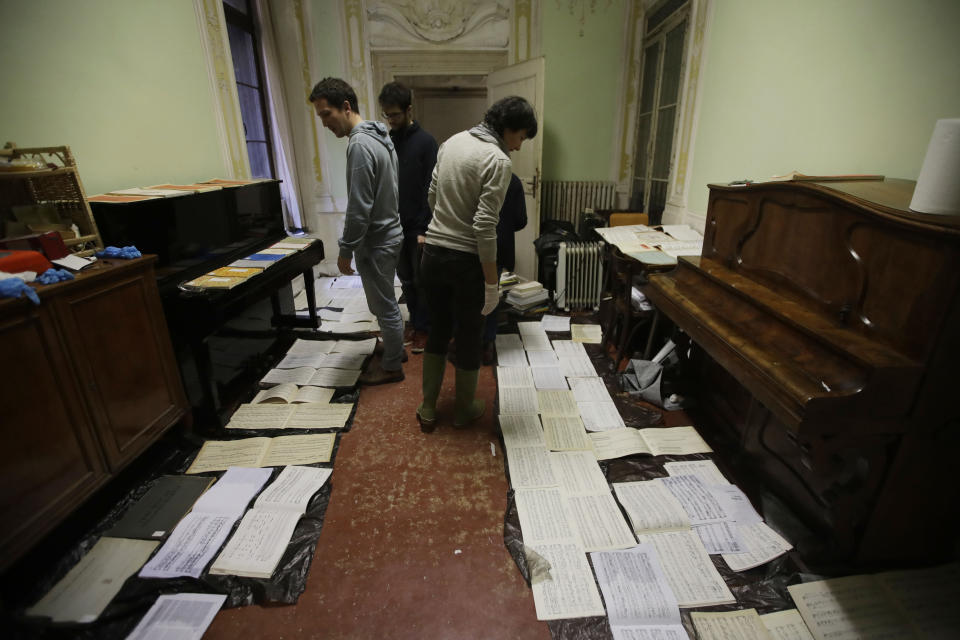 Volunteers try to save ancient music sheets by placing them to dry at the first floor of Venice Conservatory after recovering them from ground floor, Italy, Saturday, Nov. 16, 2019. High tidal waters returned to Venice on Saturday, four days after the city experienced its worst flooding in 50 years. Young Venetians are responding to the worst flood in their lifetimes by volunteering to help salvage manuscripts, clear out waterlogged books and lend a hand where needed throughout the stricken city.(AP Photo/Luca Bruno)