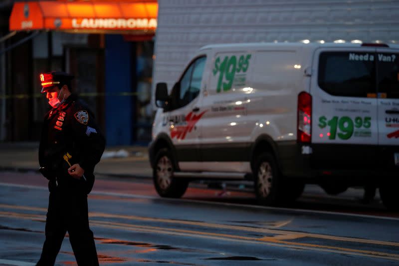 An NYPD officer stands by a van full of bodies, during the outbreak of coronavirus disease (COVID-19) at the Andrew Cleckley Funeral Home in Brooklyn, New York