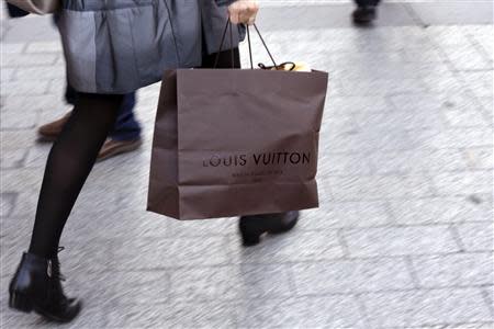 A woman walks with a Louis Vuitton shopping bag as she leaves a Louis Vuitton store in Paris September 24, 2013. REUTERS/Philippe Wojazer