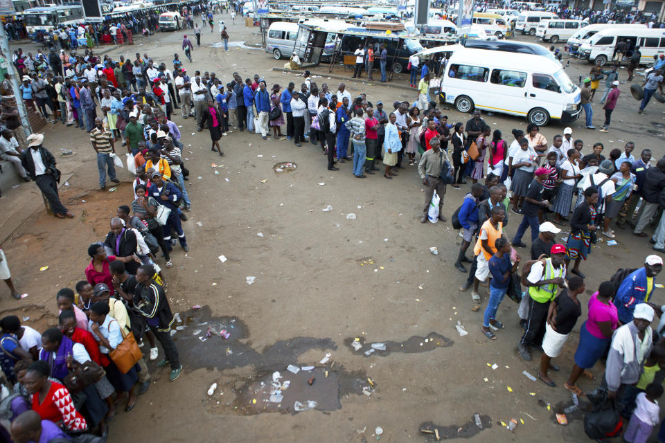 People queue for public transport in Harare, Zimbabwe, Monday, March, 23, 2020. Zimbabwe has closed its borders to non essential human traffic following its first recorded coronavirus related death. (AP Photo/Tsvangirayi Mukwazhi)