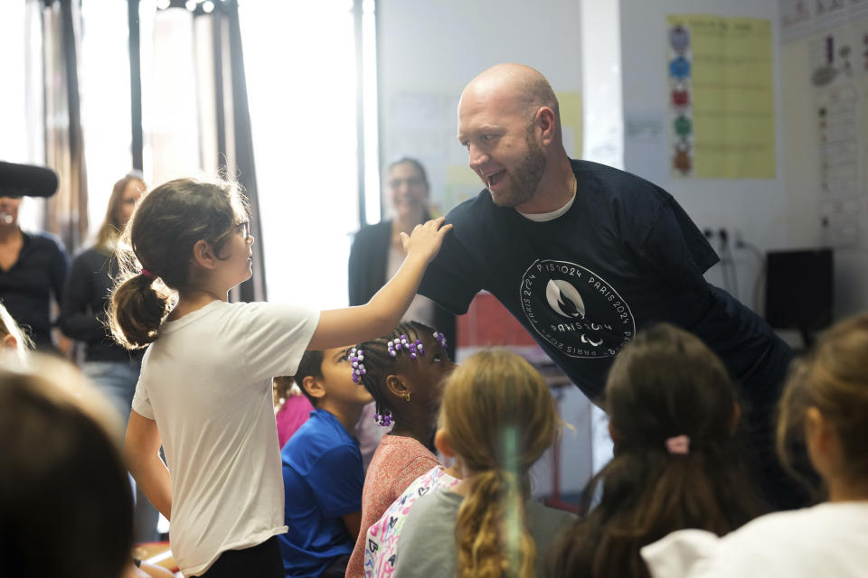 Archer Matt Stutzman of United States greets a pupil, in a Paris school, in Paris, Wednesday, Oct. 4, 2023. Visiting France's capital before Paralympic tickets go on sale next week, Stutzman dropped by a Paris school on Wednesday and wowed its young pupils with his shooting skills. (AP Photo/Thibault Camus)