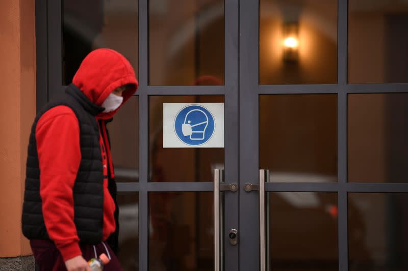 A man walks past a door with a sign reminding people to wear face mask prior to an ordered lock-down due to the further spreading of the coronavirus disease (COVID-19) in Pfarrkirchen