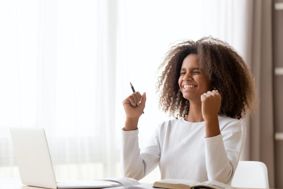 Schoolgirl sitting at desk feels happy after receiving great news