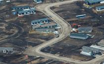 Aerial view of a residential neighborhood in Fort McMurray, Canada, where some homes have been rebuilt but many have not, one year after a massive forest fire