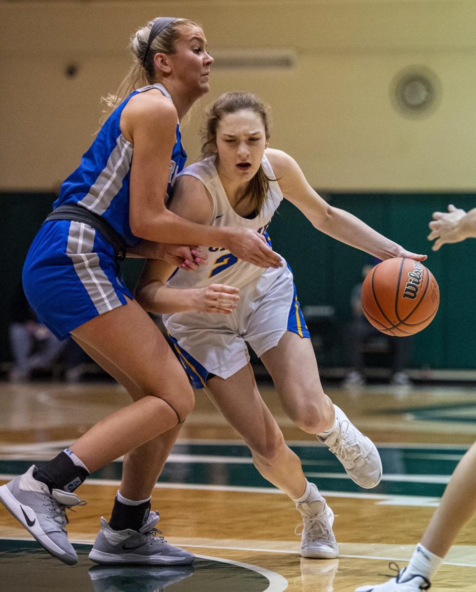 Carmel High School sophomore Kate Clarke (25) drives the ball into the defense of Hamilton Southeastern High School senior Sydney Parrish (33) during the first half of an IHSAA Girlsâ€™ Basketball Sectional game, Tuesday, Feb. 4, 2020, at Westfield High School.