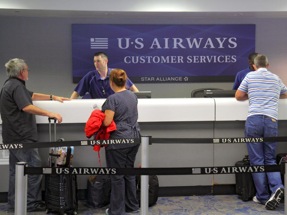 four people talk to 2 employees at a US Airways Customer Service desk