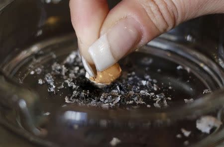 A woman stubs out a cigarette in an ashtray in a cafe in Vienna April 10, 2015. REUTERS/Leonhard Foeger