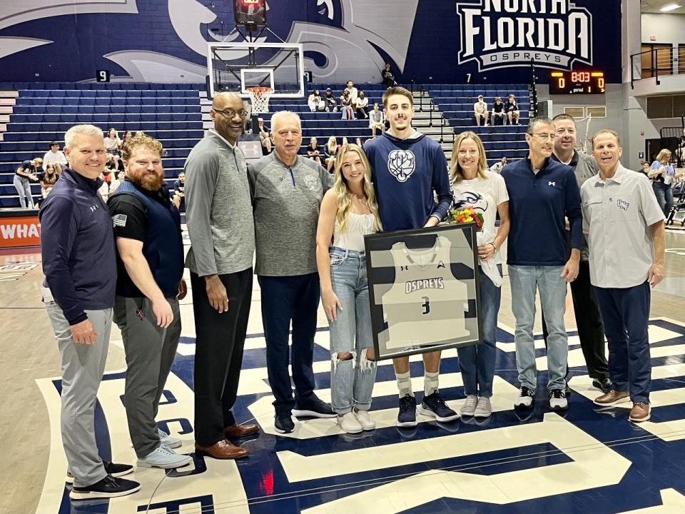 University of North Florida forward Carter Hendricksen (center) was honored on Friday during Senior Night ceremonies at UNF Arena. From the left is UNF associate head coach Bobby Kennen, director of basketball operations Chase Driscoll, assistant coaches Bruce Evans and Donny Holland, Hendricksen's girlfriend and UNF student-athlete Callie Workman, Hendricksen's parents Anita and Mark Hendricksen, assistant coach Stephen Perkins and head coach Matthew Driscoll.