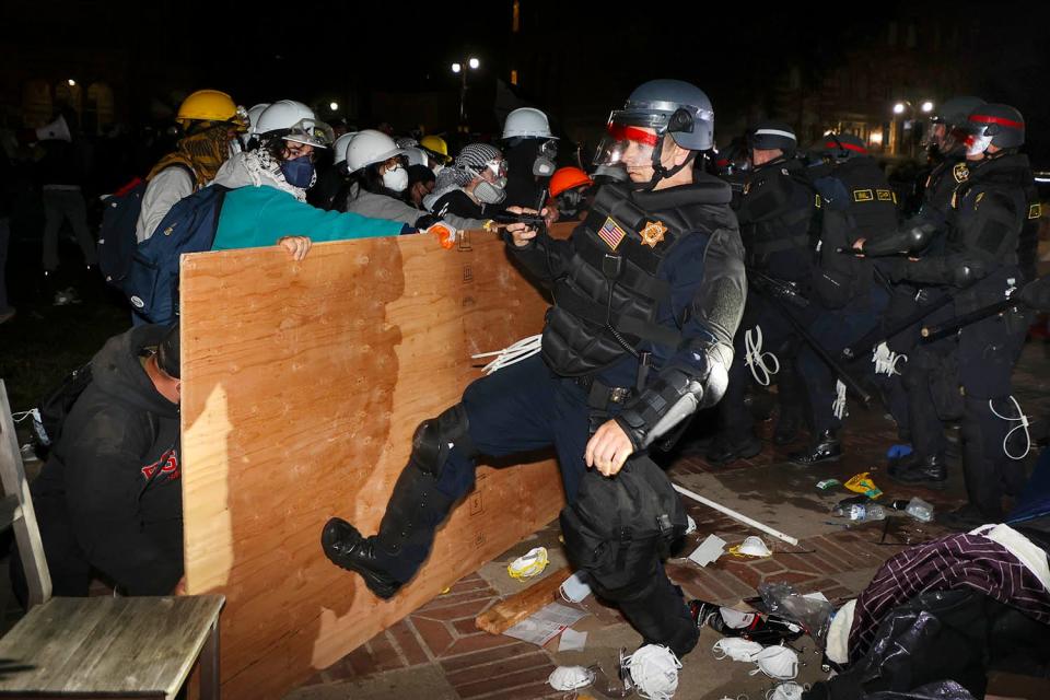 A California Highway Patrol officer kicks a wooden piece of plywood that was used to construct the barricade on the eastern wall of the Gaza Solidarity Encampment. Pro-Palestinian protesters clashed with law enforcement when authorities moved in to clear demonstrator encampments on UCLA's campus on May 2, 2024, in Los Angeles.