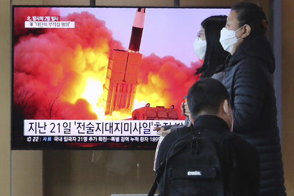 People pass by a TV screen showing a file image of North Korea's missile launch during a news program at the Seoul Railway Station in Seoul, South Korea, Sunday, March 29, 2020. North Korea on Sunday fired two suspected ballistic missiles into the sea, South Korea said, calling it "very inappropriate" at a time when the world is battling the coronavirus pandemic. The Korean letters read: "March 21, Tactical Missile." (AP Photo/Ahn Young-joon)