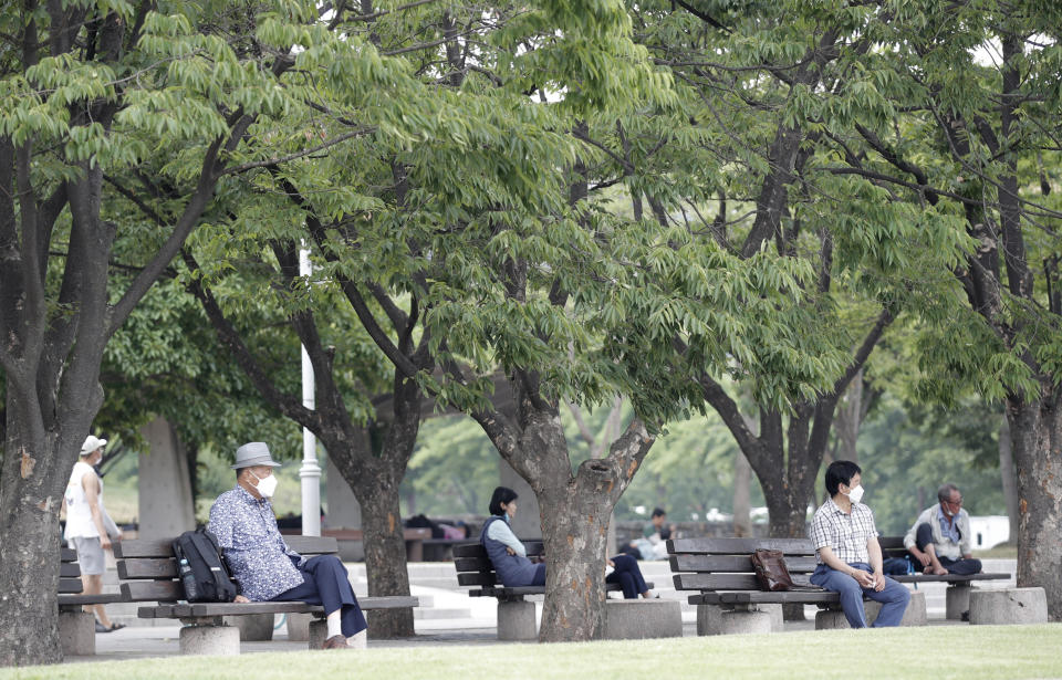 Visitors wearing face masks to prevent the spread of the new coronavirus sit on benches while maintaining social distancing at a park in Seoul, South Korea, Saturday, June 20, 2020. (AP Photo/Lee Jin-man)