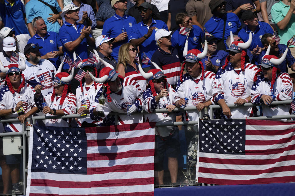 United States fans in the stands on the 1st tee wait for the start of the final day singles matches at the Ryder Cup golf tournament at the Marco Simone Golf Club in Guidonia Montecelio, Italy, Sunday, Oct. 1, 2023. (AP Photo/Alessandra Tarantino)