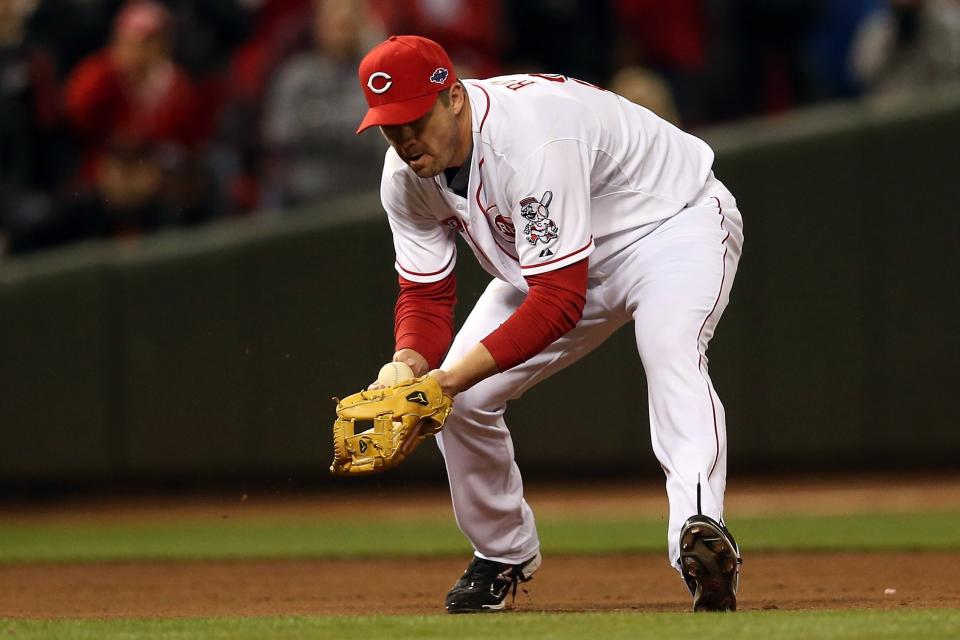 Scott Rolen #27 of the Cincinnati Reds makes an error at third base on a ball hit by Joaquin Arias #13 of the San Francisco Giants allowing the eventual game-winning run to score by Buster Posey #28 in Game Three of the National League Division Series at the Great American Ball Park on October 9, 2012 in Cincinnati, Ohio. (Photo by Jonathan Daniel/Getty Images)