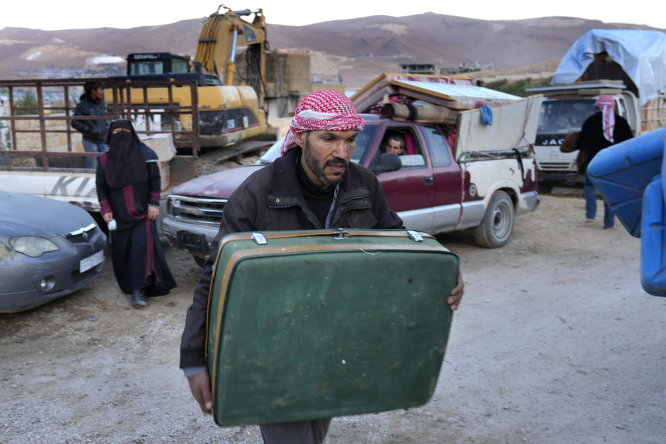 A Syrian refugee man carries his luggage, as he prepares to go back home to Syria, in the eastern Lebanese border town of Arsal, Lebanon, Wednesday, Oct. 26, 2022. Several hundred Syrian refugees boarded a convoy of trucks laden with mattresses, water and fuel tanks, bicycles – and, in one case, a goat – Wednesday morning in the remote Lebanese mountain town of Arsal in preparation to return back across the nearby border. (AP Photo/Hussein Malla)