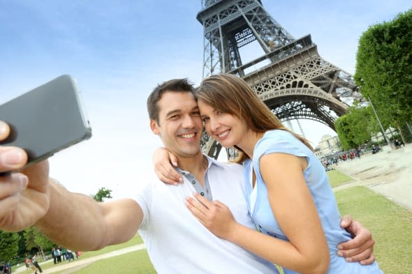 Couple in Paris taking pictures in front of Eiffel Tower