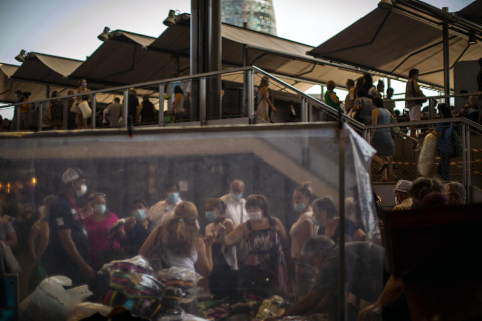 Customers wearing face masks buy sandals at a market in Barcelona on Wednesday, July 8, 2020. Spain's northeastern Catalonia region will make mandatory the use of face masks outdoors even when social distancing can be maintained, regional chief Quim Torra announced Wednesday. (AP Photo/Emilio Morenatti)