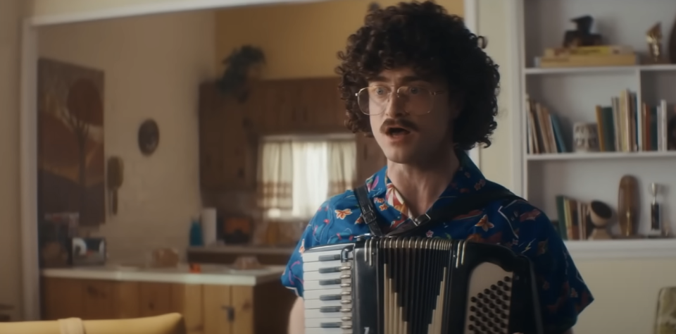 Daniel as Al playing the accordion in the living room