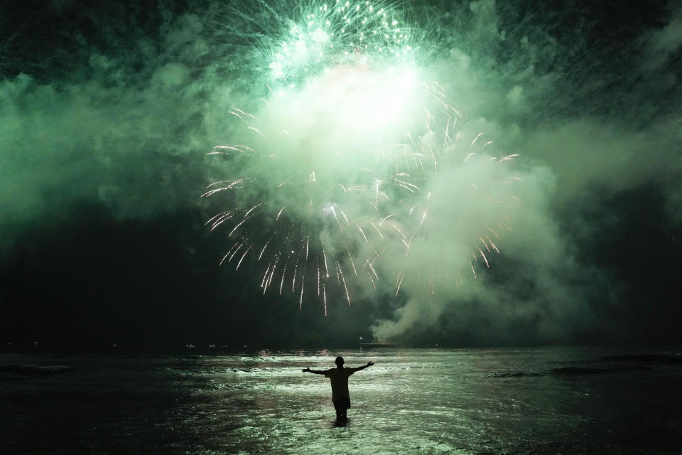 En esta imagen de archivo, un hombre celebra el inicio del año nuevo en el mar mientras observa el espectáculo pirotécnico sobre la bahía de Santos, en Santos, Brasil, el 1 de enero de 2023. (APFoto/Matías Delacroix, archivo)