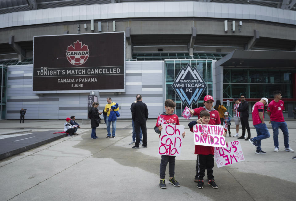 Young fans hold signs and make thumbs-down gestures outside B.C. Place stadium after the Canadian national men's soccer team's friendly match against Panama was canceled due to a labor dispute, in Vancouver, British Columbia, Sunday, June 5, 2022. (Darryl Dyck/The Canadian Press via AP)