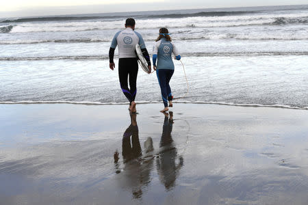 Carmen Lopez Garcia, Spain's first blind female surfer who is to participate in the ISA World Adaptive Surfing Championship, walks with her coach Lucas Garcia before training at Salinas beach, Spain, December 5, 2018. REUTERS/Eloy Alonso