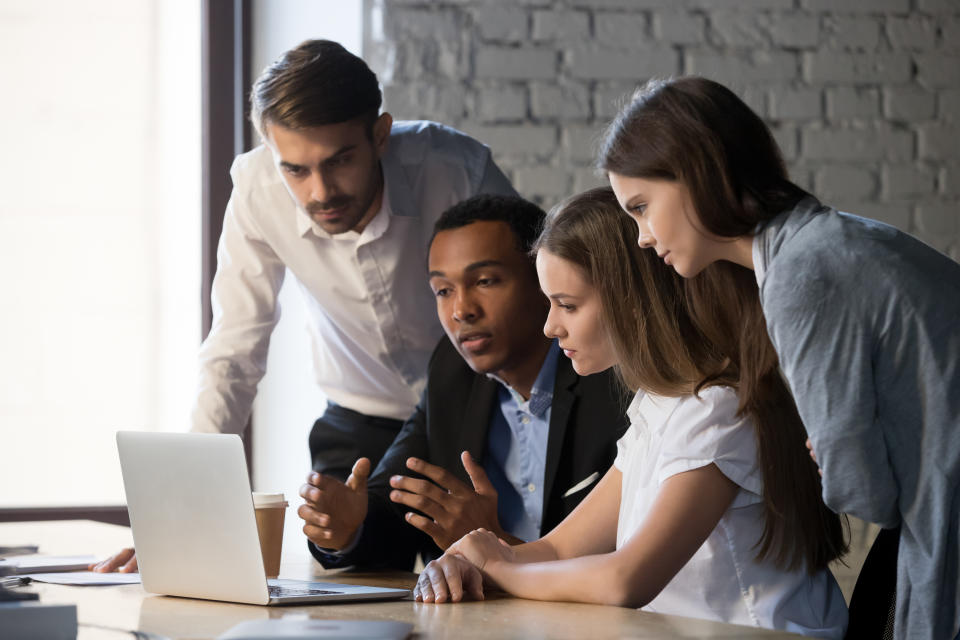 Diverse millennial workers cooperating, working together at laptop discussing business project in office, multiracial young businesspeople collaborate talking and sharing ideas on strategy success